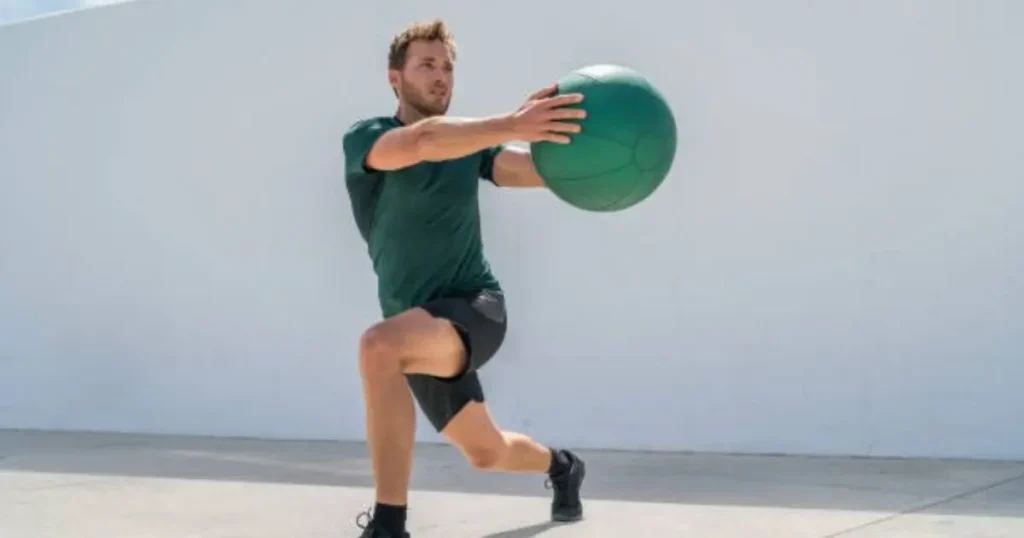 A man in athletic attire is performing a medicine ball throw exercise outdoors, demonstrating strength and focus.