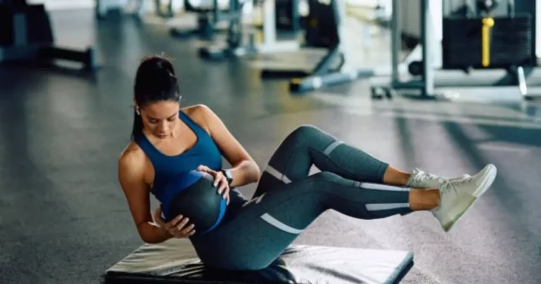 "A woman is performing an exercise with a medicine ball on a gym bench."