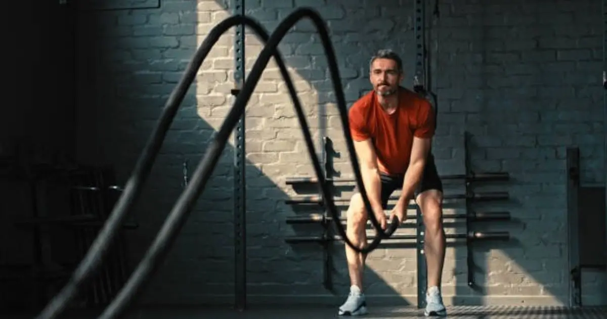"A man is performing a battle rope exercise in an urban outdoor setting."